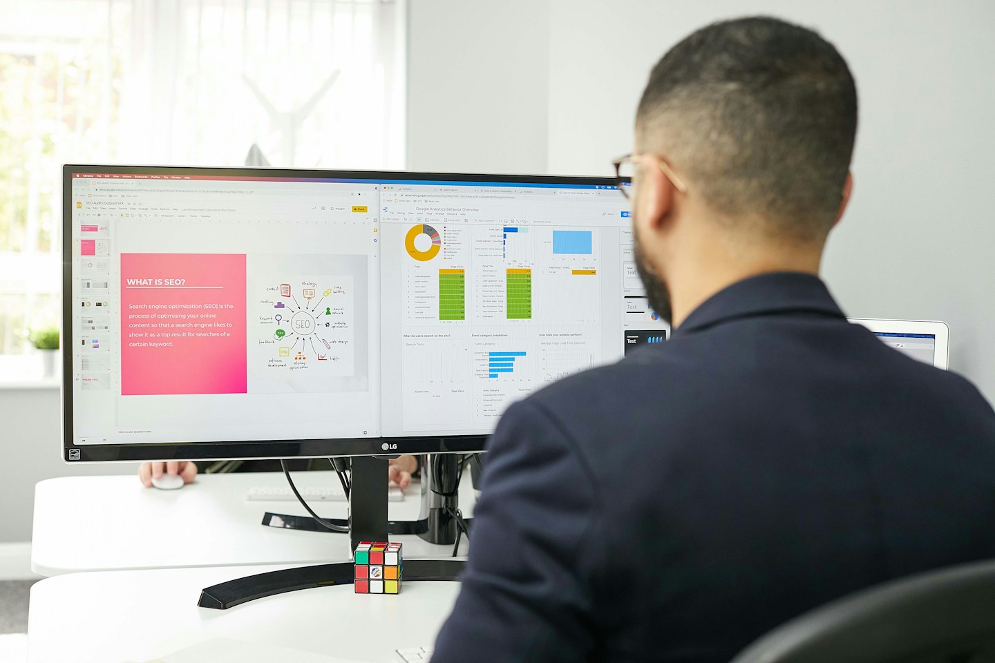 Man werkt op dubbele computermonitors met SEO en analyses.